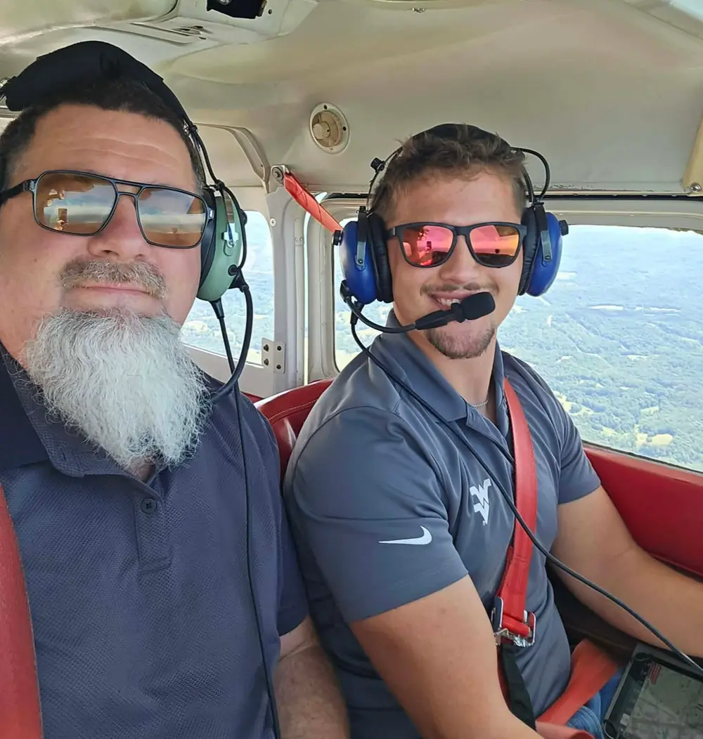 Noah Wince flying from the right seat of a high-wing airplane, with a passenger beside him
